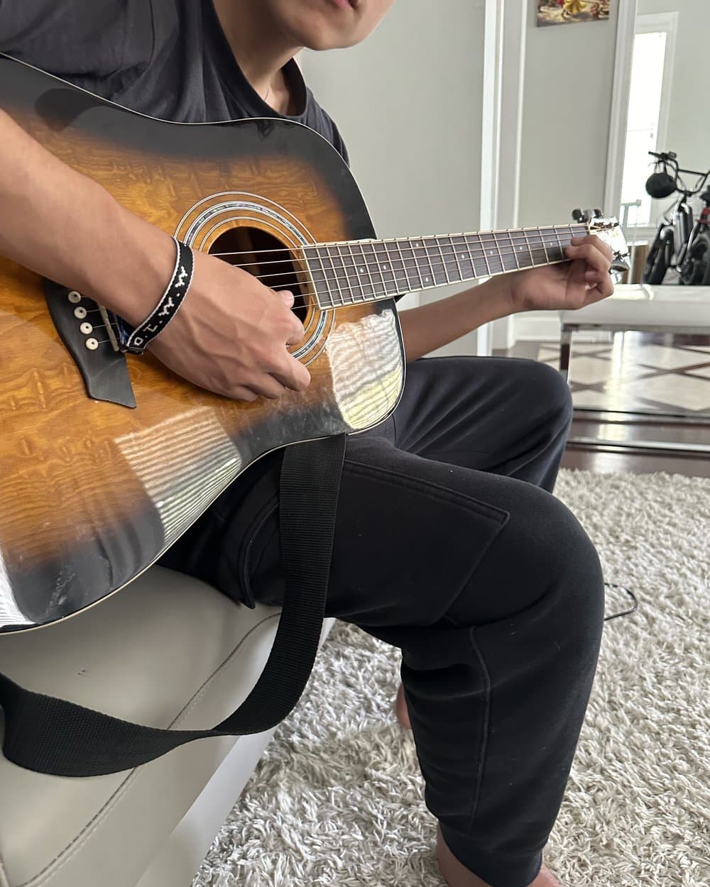 A teen learning guitar at home